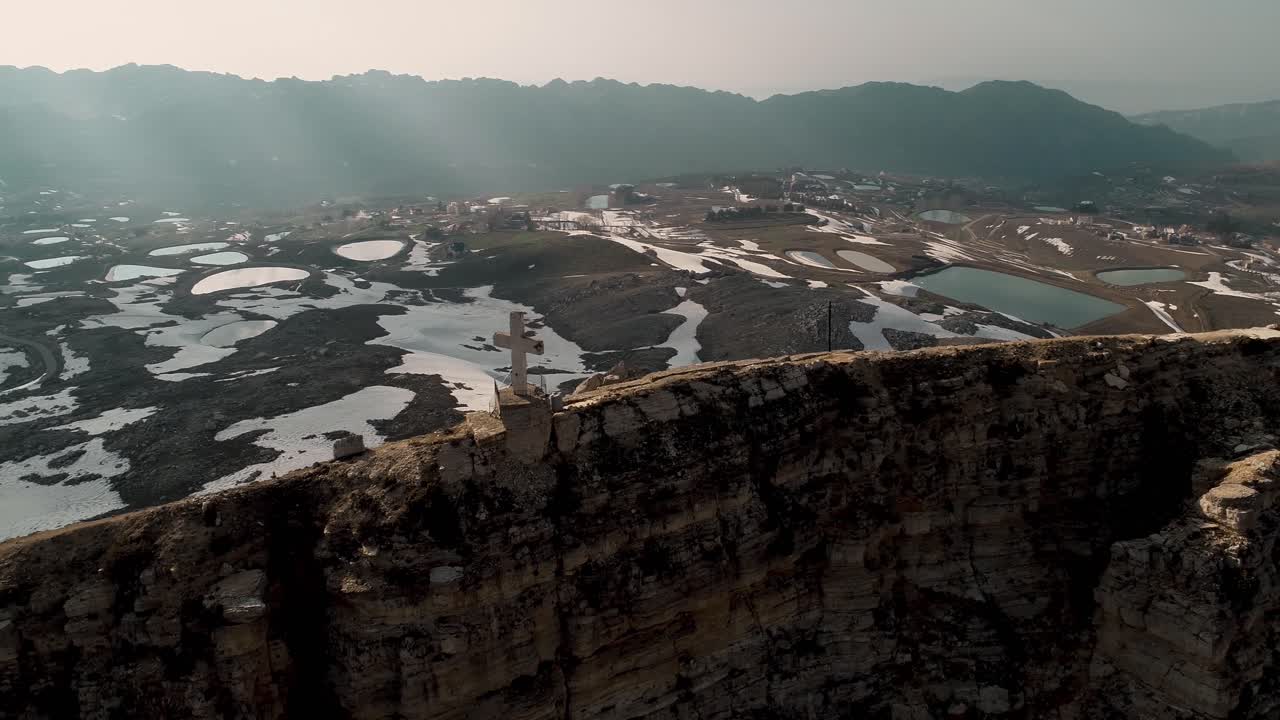 Aerial flight parallel with cross on mountain ridge and view of landscape