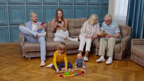 Happy-multigenerational-family-leisure-at-home-couple-parents-and-grandpagents-relaxing-on-sofa