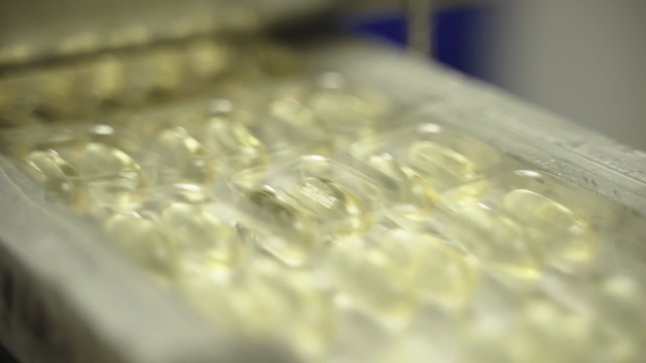 Close-up view of transparent yellow capsules in production tray ready for packaging.