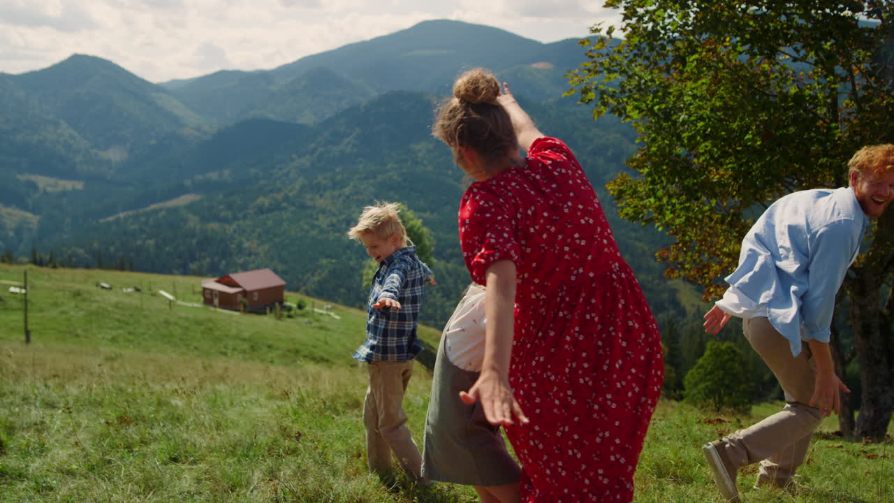 семья бежит, как самолет на горной лужайке. смешные люди разворачивают руки.
