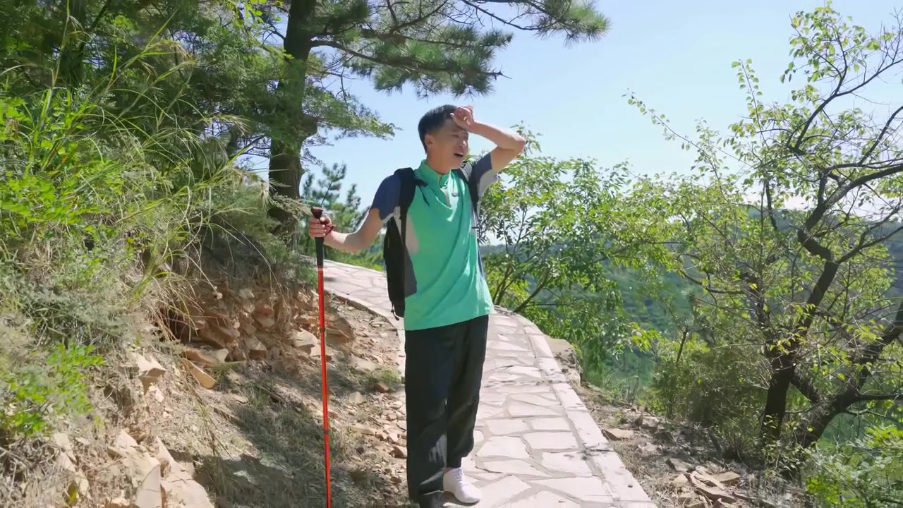 Hombre senderista mochilero con estilo de vida activo y cansado, secándose el sudor mientras hace senderismo y trota por un sendero de montaña y bosque a través de un paisaje alpino, concepto de aventura, libertad y recreación al aire libre.