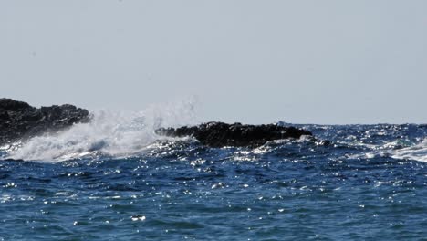 Scenic-view-of-sea-waves-crashing-onto-rocks-with-water-splashes,-Jerusalem-Beach-in-Erisos,-Greece---wide,-static