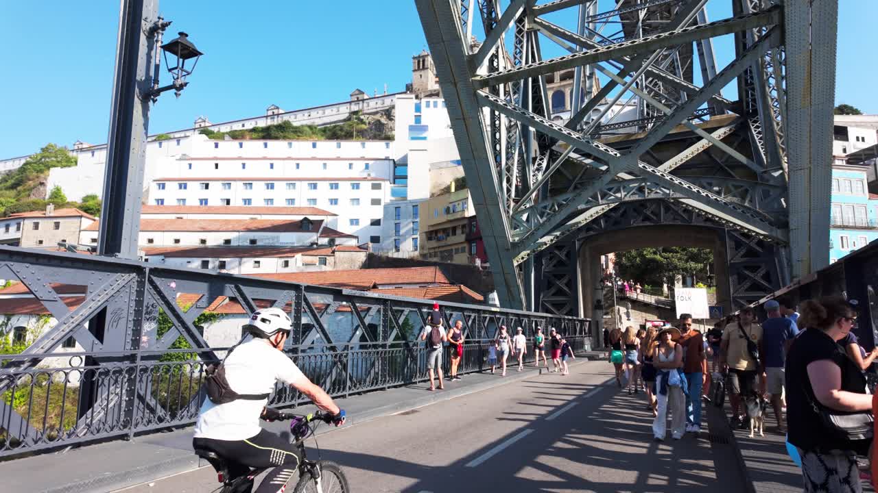 People walking on the Luís I Bridge in Porto on a sunny day with views of the city and river