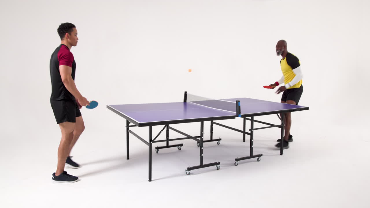 Playing table tennis, two men competing in friendly match indoors