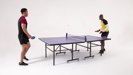 playing table tennis, two men competing in friendly match indoors
