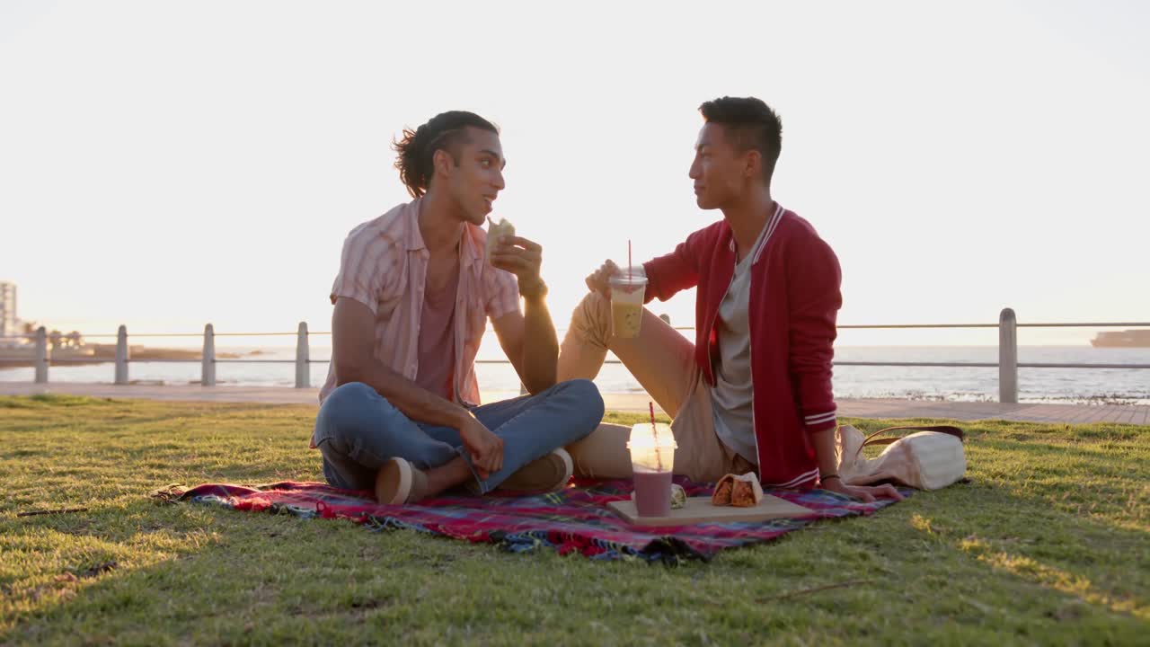 해변의 산책로에서 피크닉을 하는 행복한 다양한 동성애자 남성 커플, 슬로우 모션