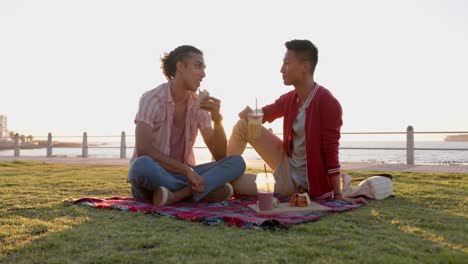 happy diverse gay male couple having picnic at promenade by the sea, slow motion