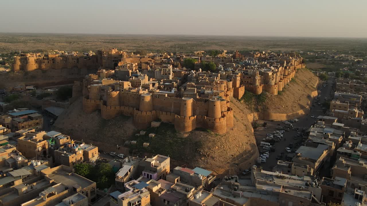 Aerial drone shot of Jaisalmer Fort basking in the golden hour with long shadows and soft orange light.