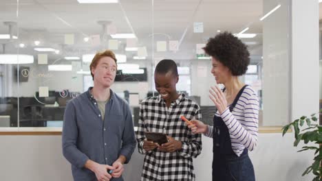 diverse male and female business colleagues discussing by glass wall in office