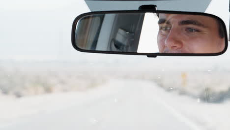 joven blanco conduciendo, visto en el espejo retrovisor, de cerca