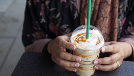 woman holding a caramel frappuccino