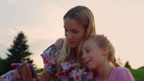 Familia-Tomando-Selfie-En-El-Parque-De-La-Ciudad.-Mujer-Y-Niña-Mirando-Al-Teléfono-Celular-Al-Aire-Libre.