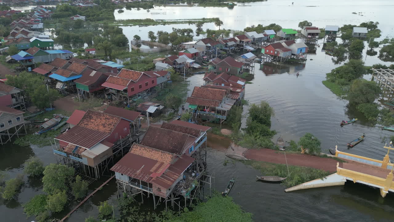 Cluster of colorful stilt houses rises above Tonlé Sap’s high waters, boats moored below