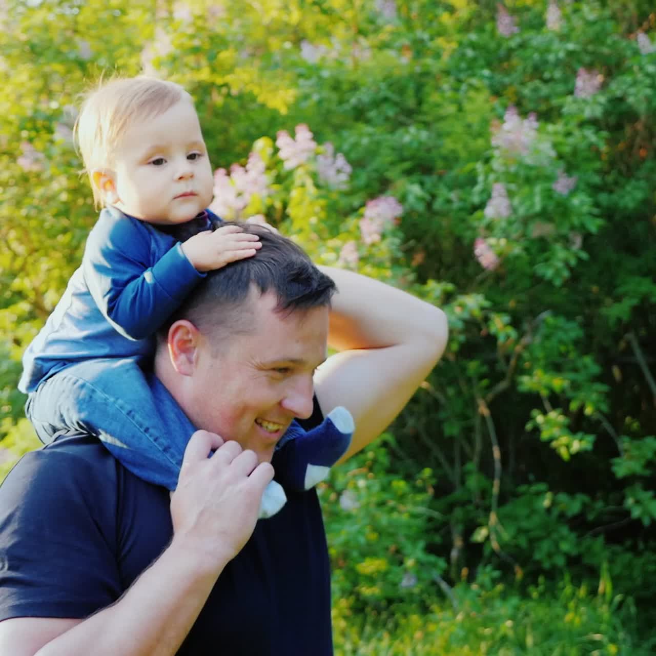 un joven padre caucásico lleva a su hijo sobre sus hombros