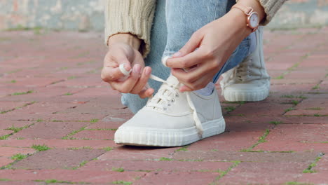 hands of woman tie shoes or sneakers on pavement