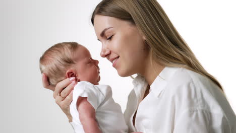 beautiful portrait of a mother with her newborn baby. loving woman holding her child close to the lips. white backdrop.