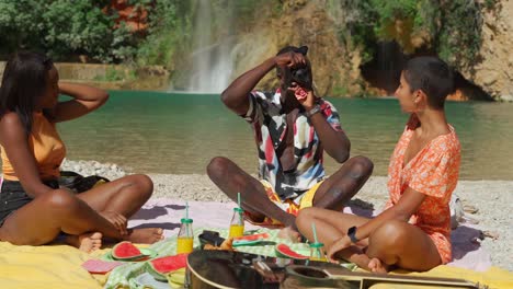 black man taking photo of women sitting on beach