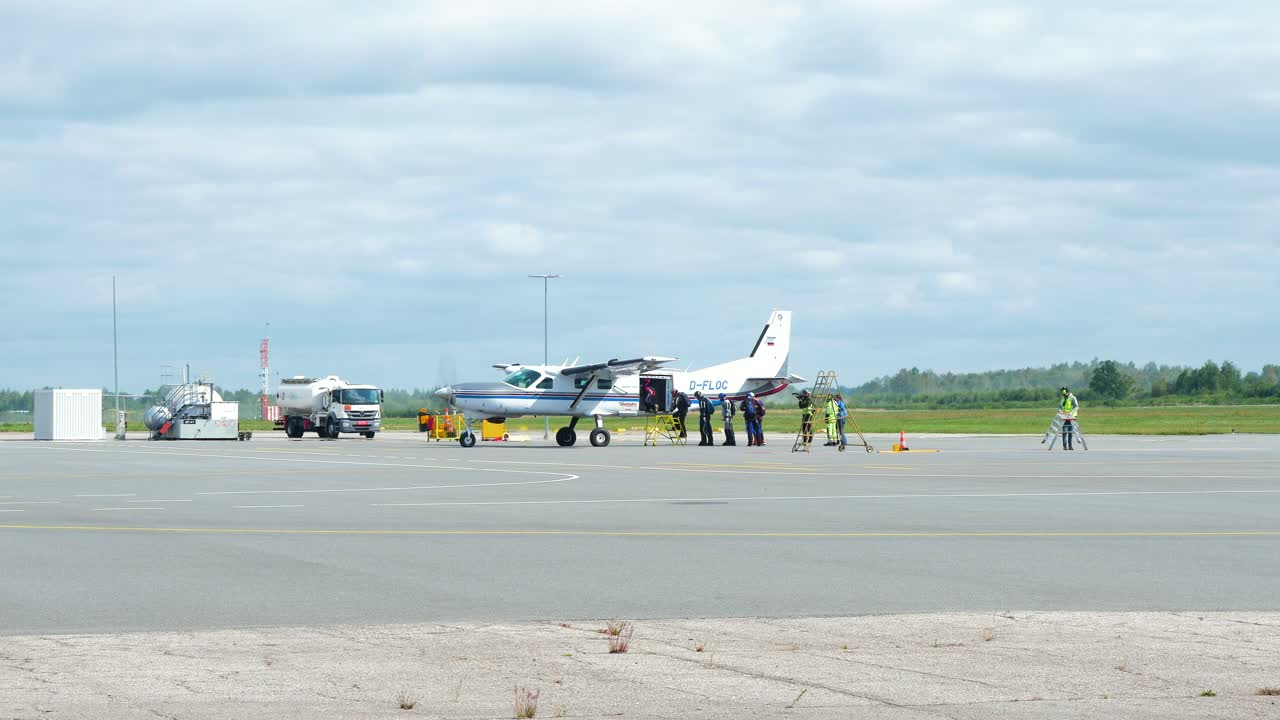 높은 고도 낙하산 점프, 화창한 여름날, 중간 거리 샷을 위해 하늘로 올라가기 전에 흰색 단일 날개 항공기로 이동하는 전문 스카이다이버 그룹