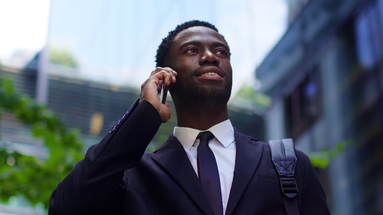 primer plano de un joven empresario vestido con un traje hablando por teléfono móvil de pie fuera de las oficinas en el distrito financiero de la ciudad de londres, reino unido.