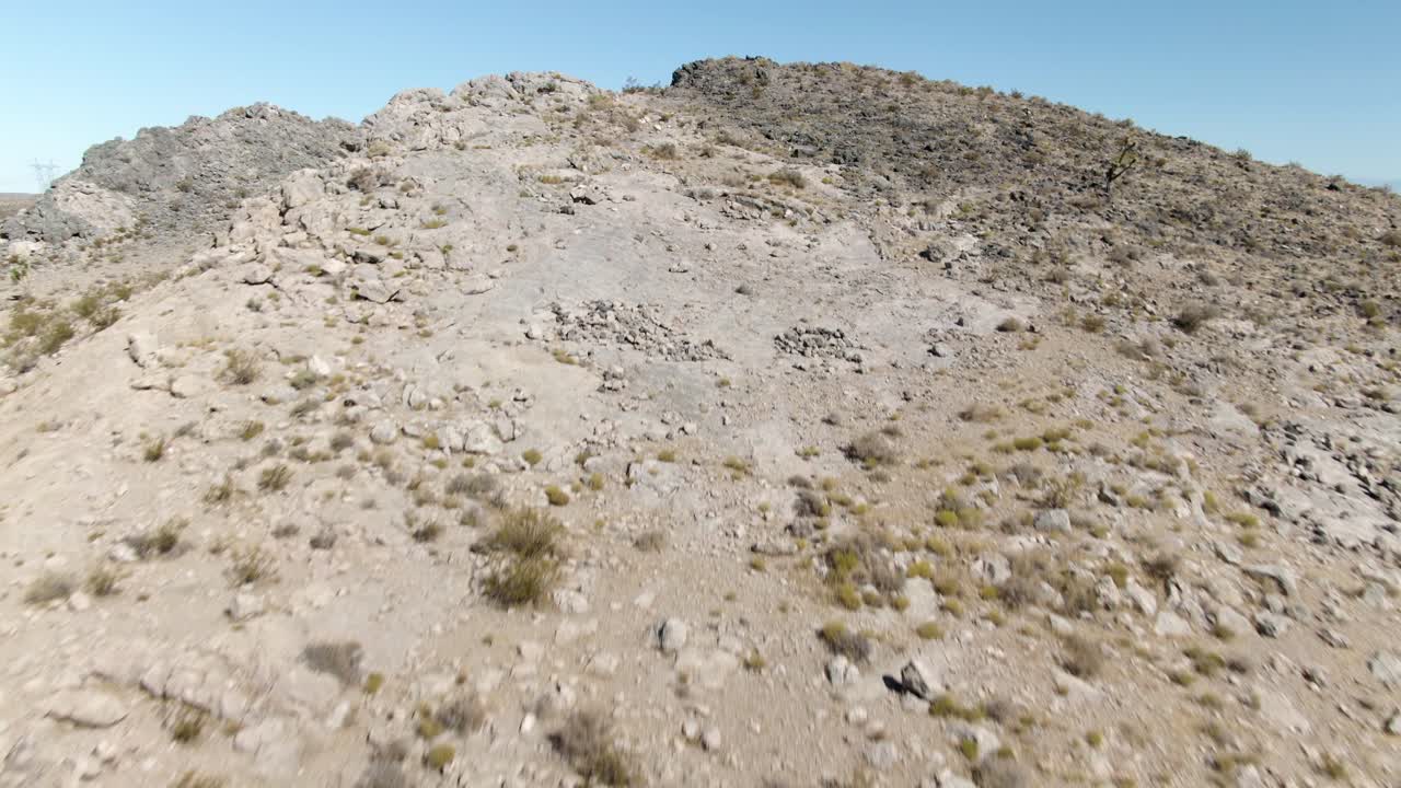 escalada aérea de baja altitud una colina rocosa moderada en el desierto de mojave a punto de revelar el vasto vacío