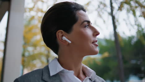 Smiling-woman-speaking-earpods-on-go-closeup.-Successful-freelancer-walk-street