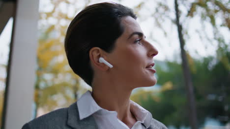una mujer sonriente hablando con auriculares en primer plano.
