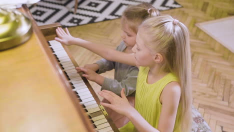 two little girls playing old piano at home