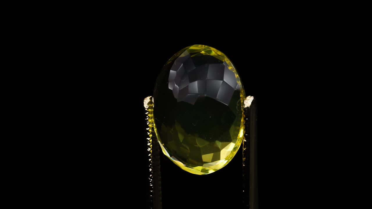 자연 황색 시트린은 회전 테이블에 있는 핀세저에 있습니다.