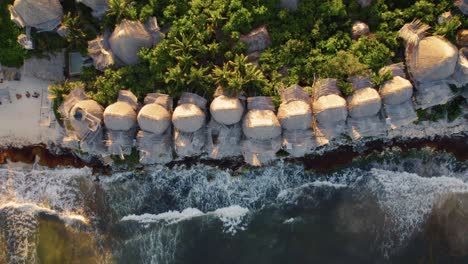 top down aerial view of azulik hotel in tulum, méxico during sunset near a beach with breaking waves