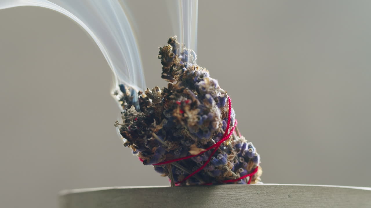 Person holding Palo Santo wood stick in hand, aromatic Palo Santo burning on black background, smoke spreading around, slow motion video clip, high quality 4k close up footage. High quality 4k footage