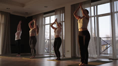 in slow motion a group of women together do yoga of different ages and weight categories thin and fat women in the gym in the morning in the sun. the glare of the sun on the floor