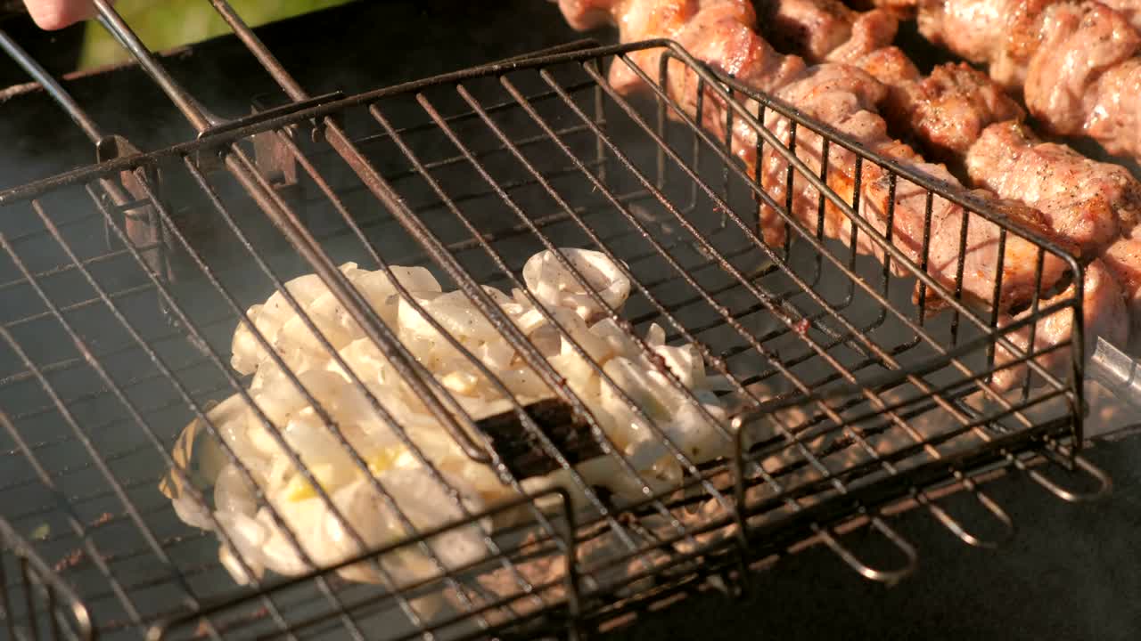 맛있는 양파와 맛있는 돼지고기 바베큐는 석탄 그릴 위에 개에 여 있습니다.