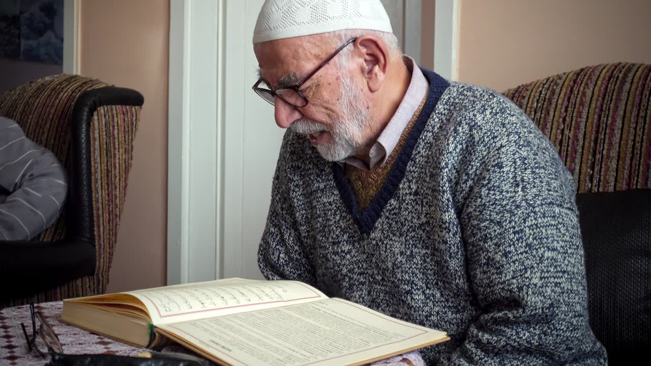 쿠피를 입은 노인 터키 무슬림 남자가 이프타르 전에 라마단에서 가장 거룩한 꾸란을 송하고 있습니다.