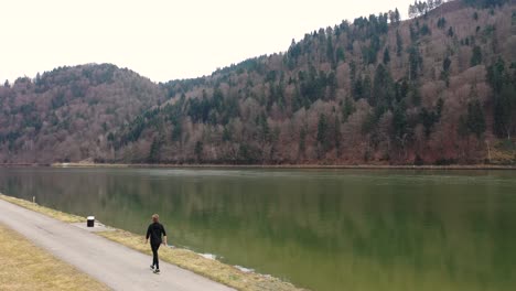 a great shot of a drone flying over a path at the edge of the river towards the river