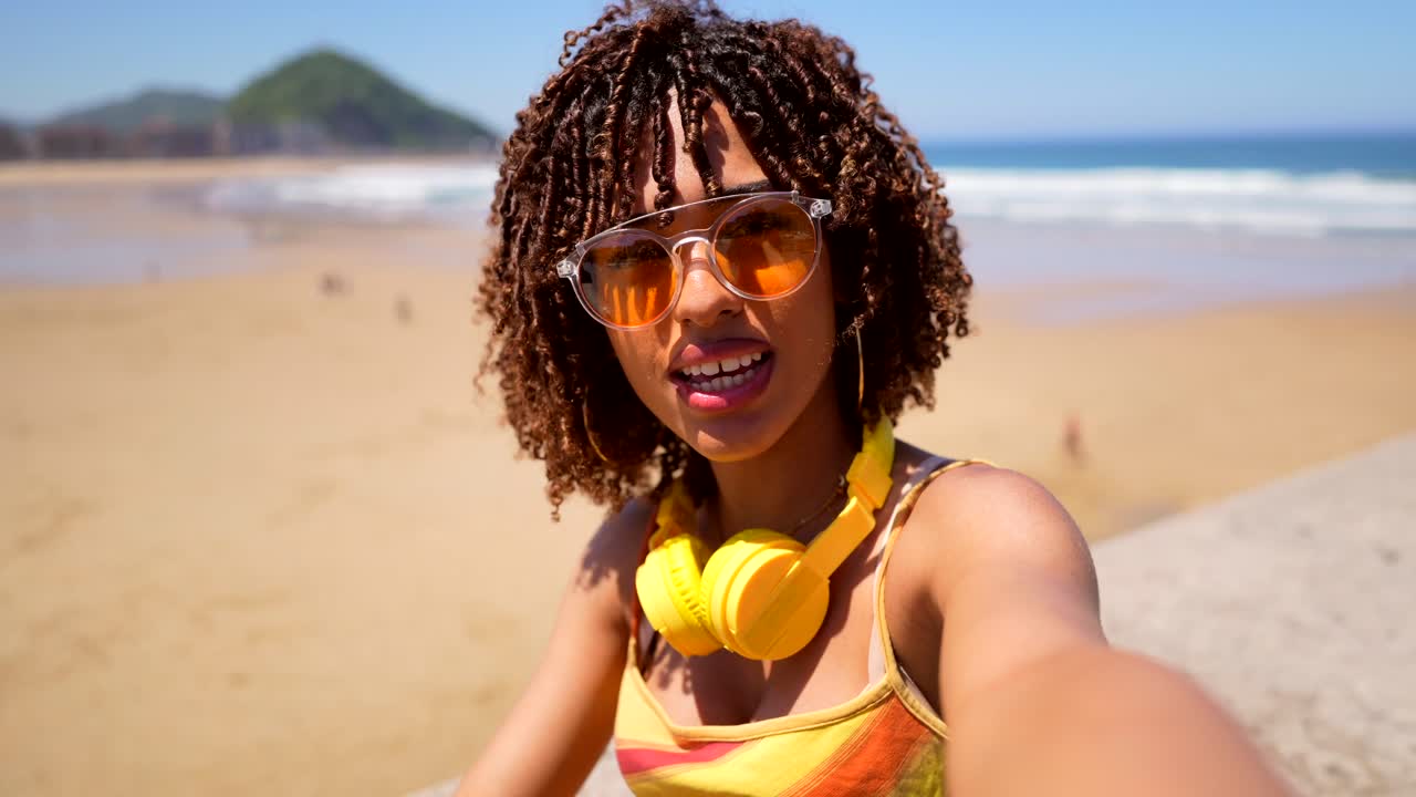 Donna con cuffie e occhiali da sole sulla spiaggia