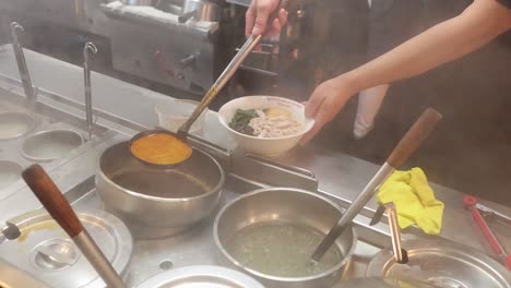 chef preparing noodles with broth and toppings