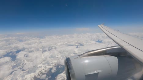 Image-from-the-airplane-window,-close-up-of-the-turbine,-passing-above-the-clouds-over-the-Swiss-Alps-between-the-clouds