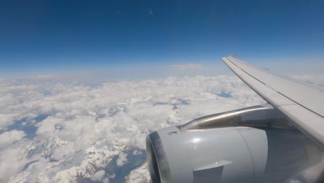 image from the airplane window, close-up of the turbine, passing above the clouds over the swiss alps between the clouds