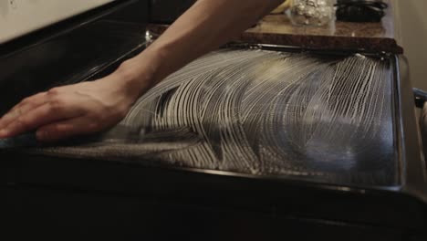 a man cleaning the glass electric stove with soap - medium shot