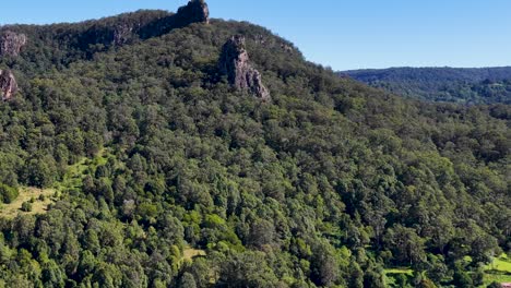 aerial footage of lush green forest and rocky formations under clear blue skies in nimbin, australia