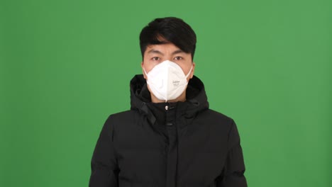man wearing a face mask in front of a green screen