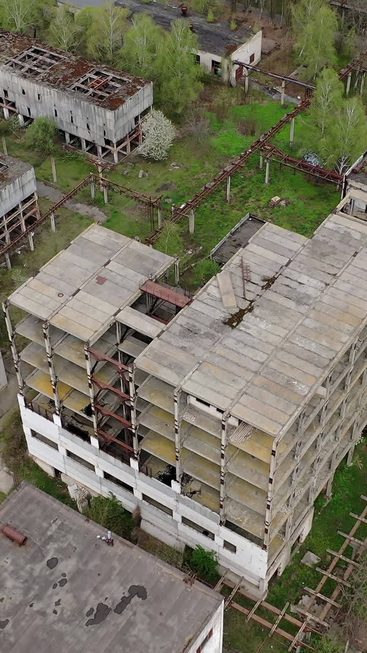 Ruined factory buildings. Abandoned warehouses or production department on the factory territory. Old industrial edifices for demolition. Aerial view. Vertical video