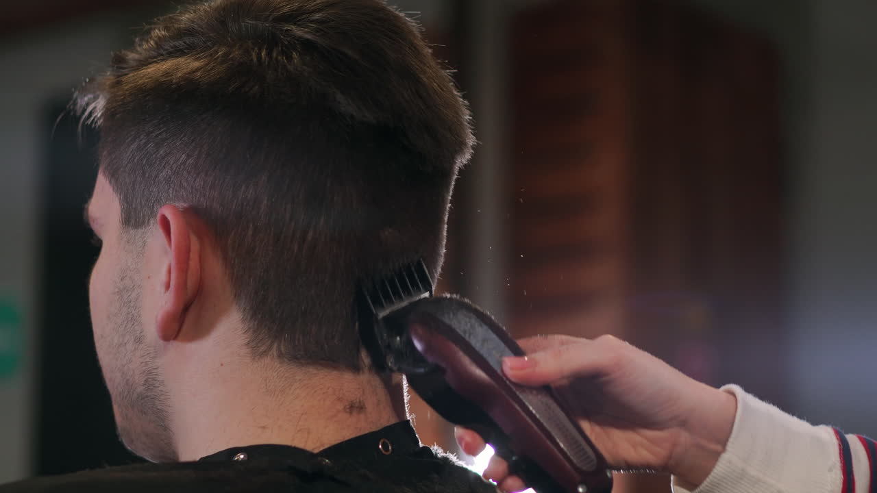 Hairdresser tools. Close up of male hands brushing electric hair clippers. Hairdressers prepare hair machine for next client. Man clean black shaving machine