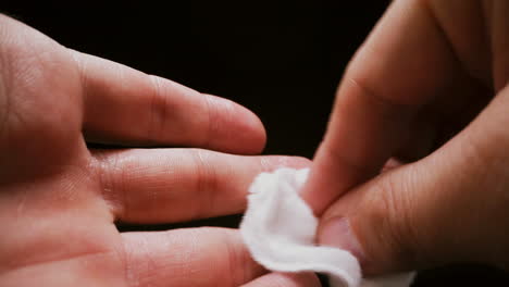 person wipes palm and fingers with cotton antiseptic patch