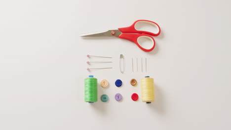 video of scissors, buttons, pins and cotton reels arranged on white background