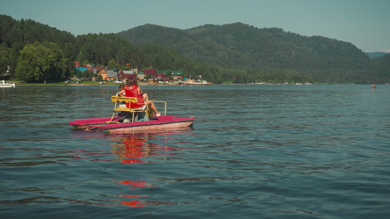 madre e hijo pedalan juntos en catamarán montando a lo largo de un río pacífico contra el pueblo disfrutando de la vista panorámica. divirtiéndose y observando la belleza de la naturaleza. vacaciones familiares