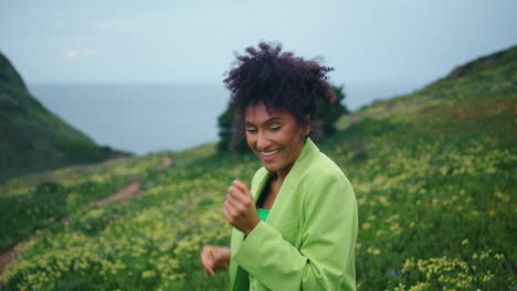 Smiling-girl-moving-body-energetically-on-cloudy-field-closeup.-Woman-performing