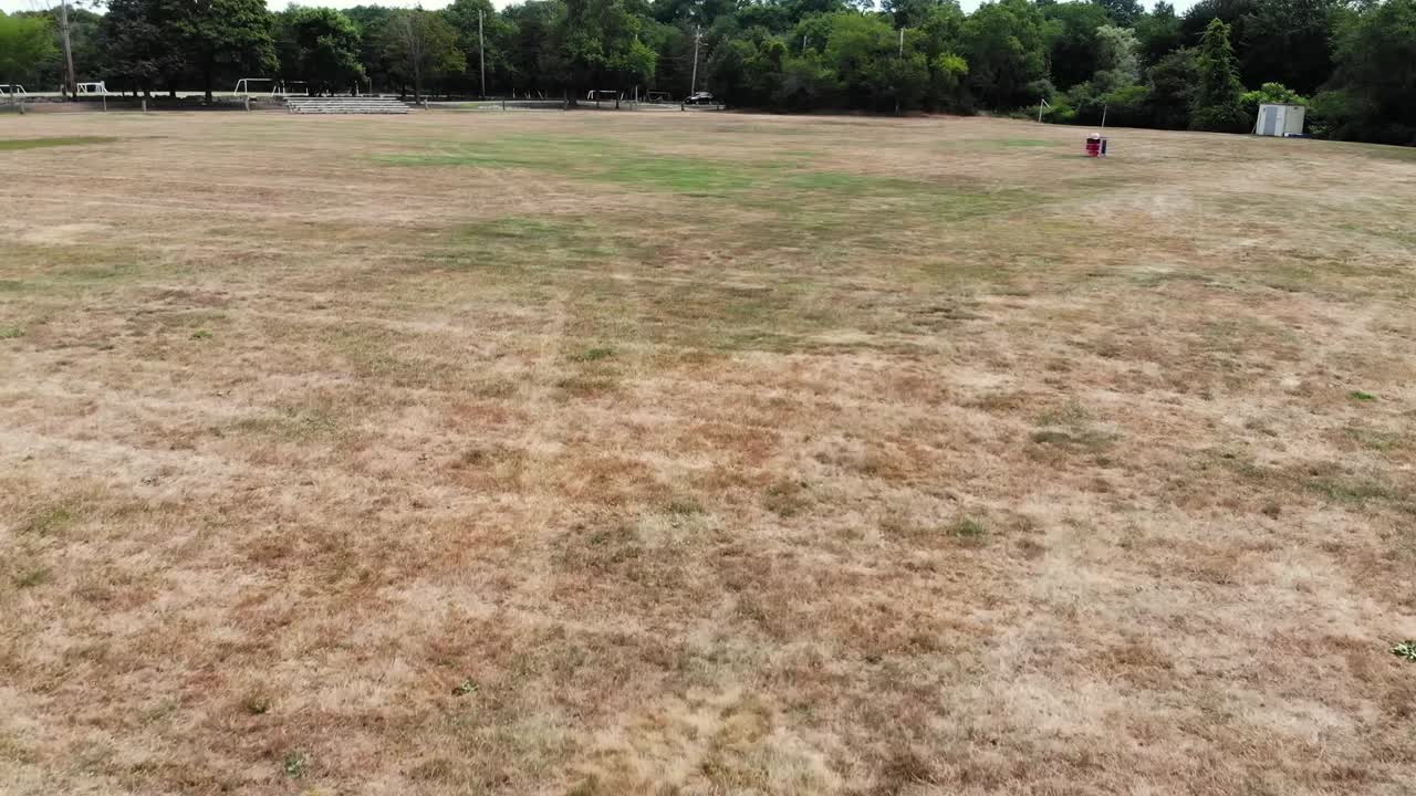 vuelo bajo de drones sobre un campo de fútbol y deportes de hierba quemada en un día nublado de verano