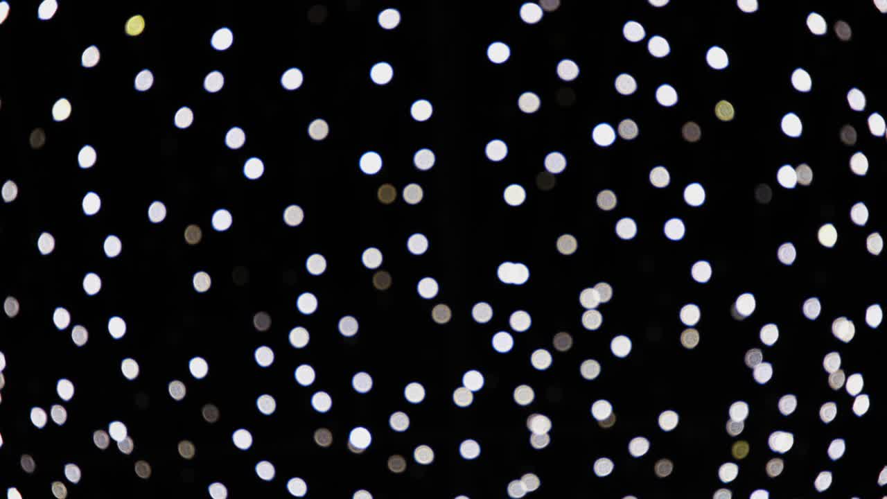 Luci bianche sfocate astratte scintillanti e luminose su sfondo nero. Concetto di festività natalizie o di Capodanno