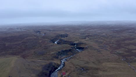 aerial backwards flight showing icelandic sela river in north iceland during cloudy autumnal day